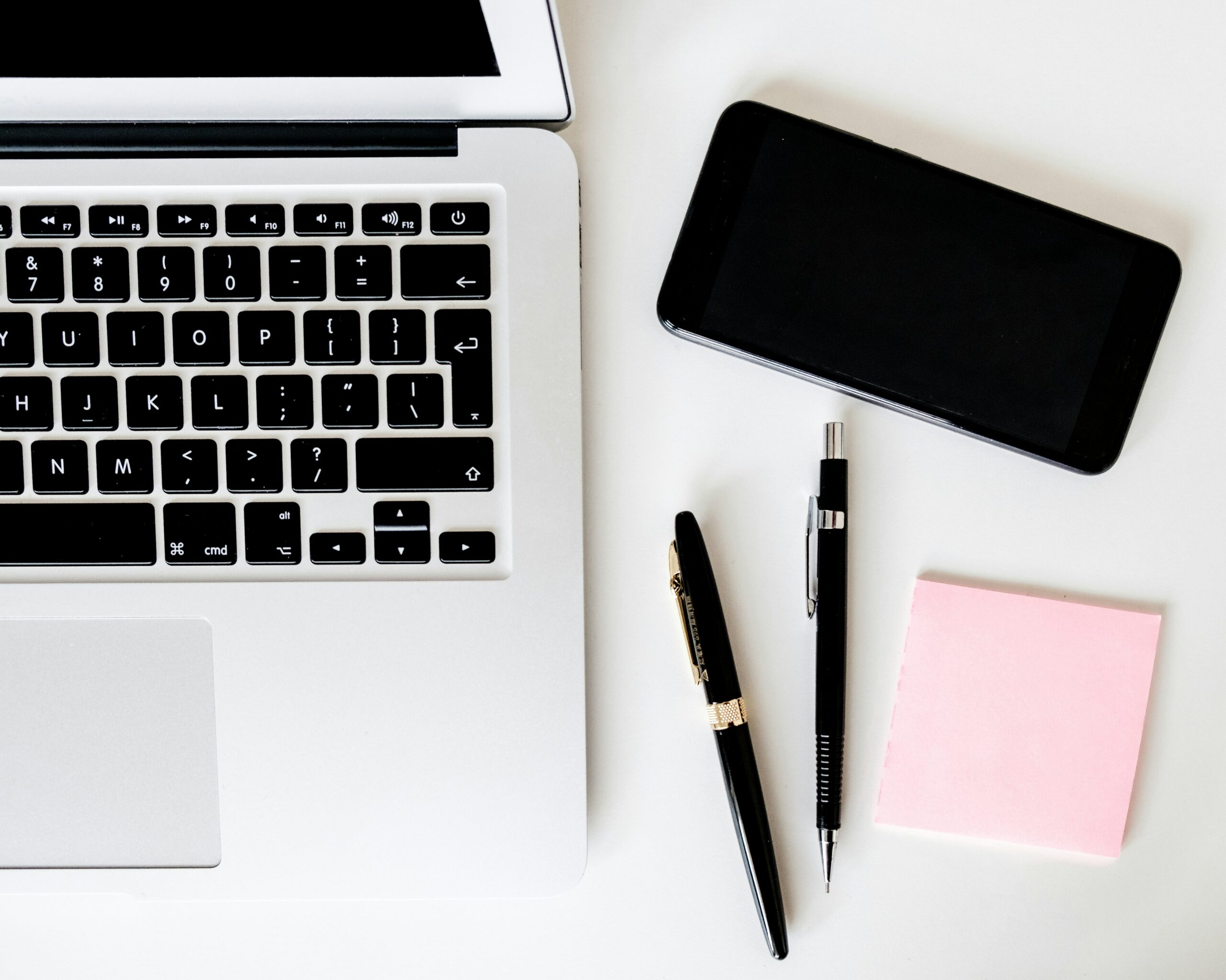 Blick auf Schreibtisch mit Laptop, Mobiltelefon und Schreibmaterial